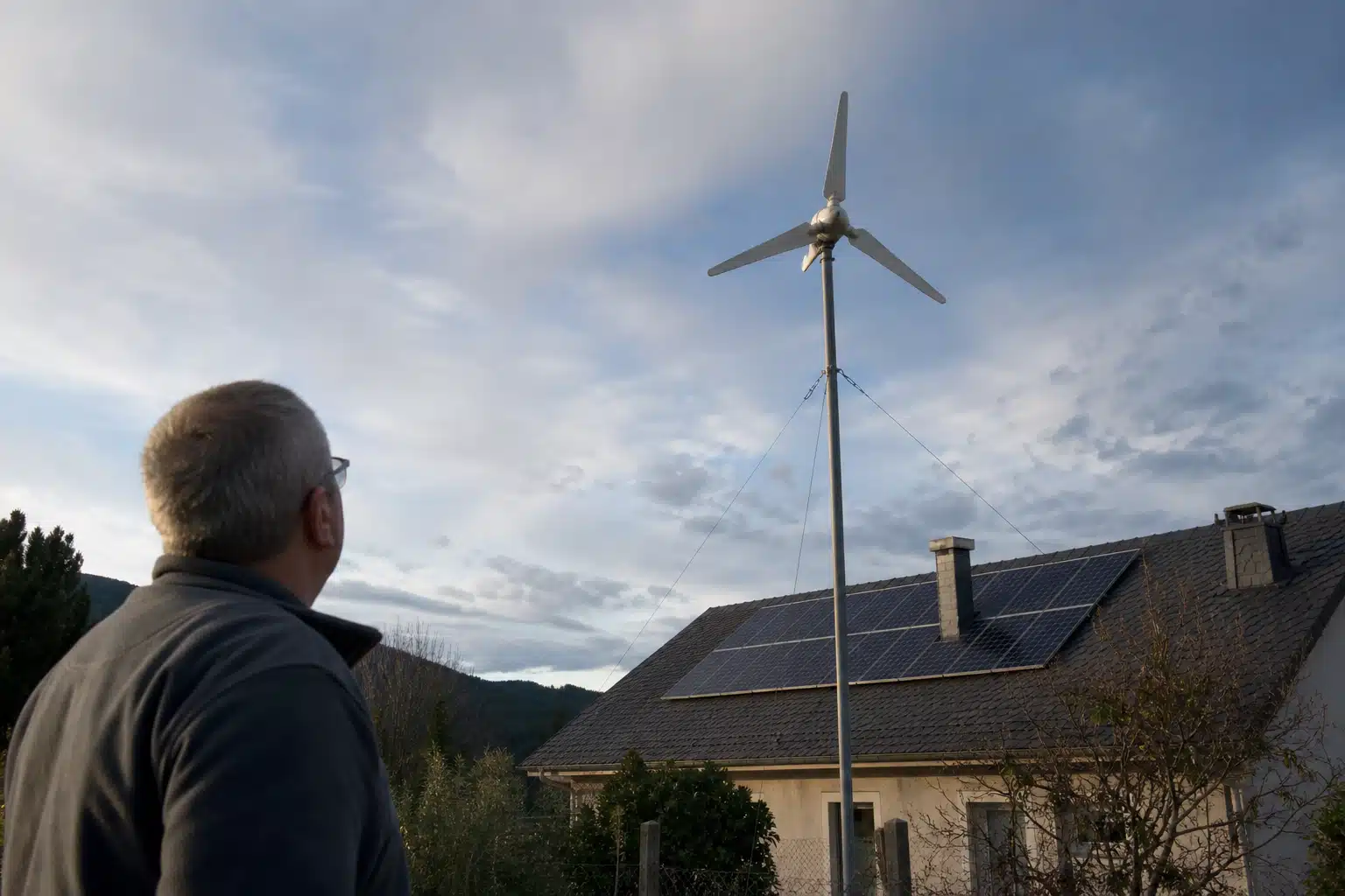 Personne regardant toit avec panneaux solaires et éolienne